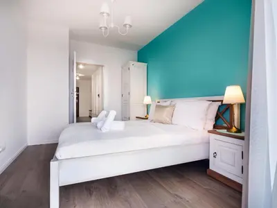 a bedroom with a white bed and a blue wall at Wislane Tarasy by Tyzenhauz in Kraków