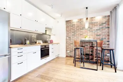 a kitchen with white cabinets and a brick wall at Tyzenhauz Apartments Piwna Street in Kraków