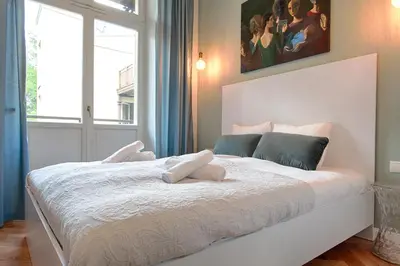 a bedroom with a large white bed with a painting on the wall at Tyzenhauz Apartments Comfort in Kraków