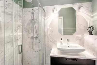 a white bathroom with a shower and a sink at Tyzenhauz Apartments Comfort in Kraków