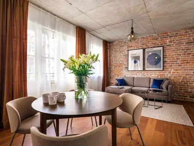 a living room with a table and chairs and a brick wall at Tyzenhauz Apartments Comfort in Kraków