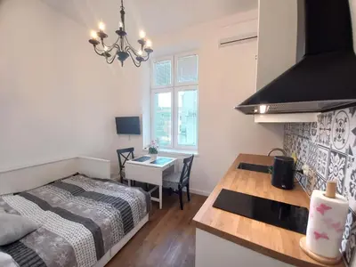 a room with a bed and a kitchen with a table at Krakowska Old Town Apartments - 16b in Kraków