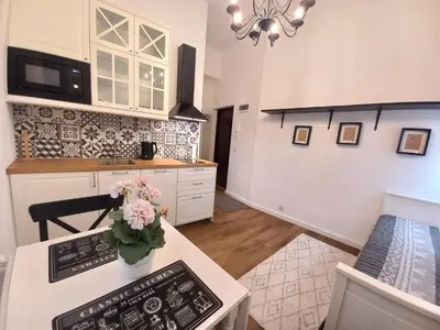 a kitchen with a table with a vase of flowers on it at Krakowska Old Town Apartments - 16b in Kraków