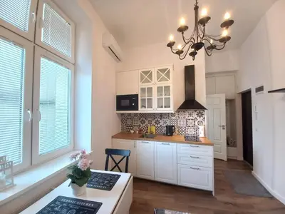 a kitchen with white cabinets and a chandelier at Krakowska Old Town Apartments - 16b in Kraków