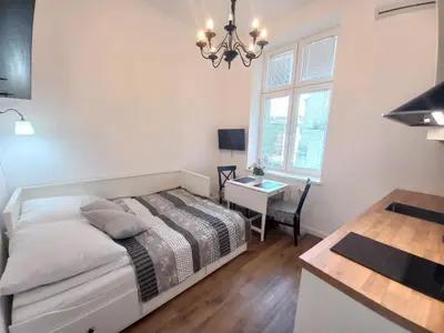 a bedroom with a bed and a desk and a window at Krakowska Old Town Apartments - 16b in Kraków
