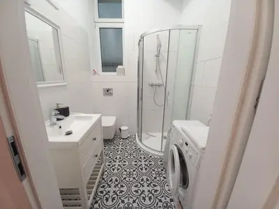 a bathroom with a shower sink and a washing machine at Krakowska Old Town Apartments - 16b in Kraków