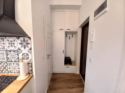 a hallway with a kitchen with white cabinets and tiles at Krakowska Old Town Apartments - 16b in Kraków