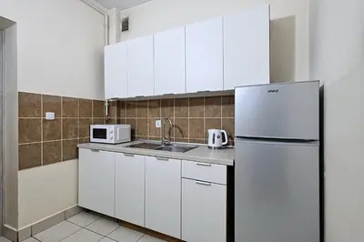 a kitchen with white cabinets and a refrigerator at Urban Nest Apartments Szewska 21 in Kraków