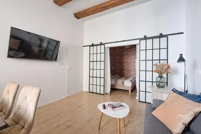 a living room with a couch and a tv on a wall at Urban Nest Apartments Szewska 21 in Kraków