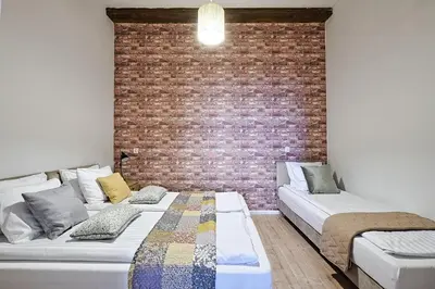two beds in a room with a brick wall at Urban Nest Apartments Szewska 21 in Kraków