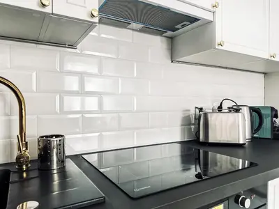 a kitchen with black counter tops and white tiles at Monkeyland - unique apartment in Old Podgorze in Kraków