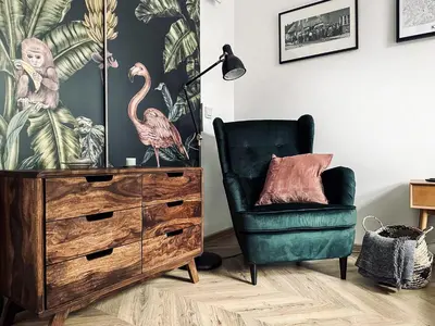 a chair and a dresser with a lamp and a flamingo wallpaper at Monkeyland - unique apartment in Old Podgorze in Kraków