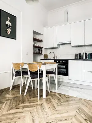 a kitchen with white cabinets and a table and chairs at Monkeyland - unique apartment in Old Podgorze in Kraków
