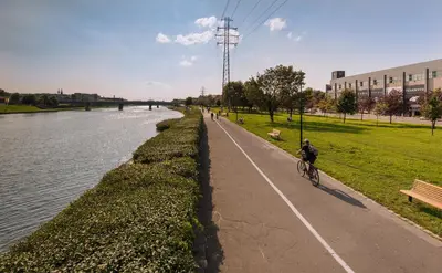 a person riding a bike on a path next to a river at ApartmentPrestige - Boulevard in Kraków