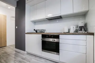 a kitchen with white cabinets and a black oven at ApartmentPrestige - Boulevard in Kraków