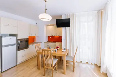 a kitchen with a wooden table with chairs and a dining room at ApartmentPrestige - Boulevard in Kraków