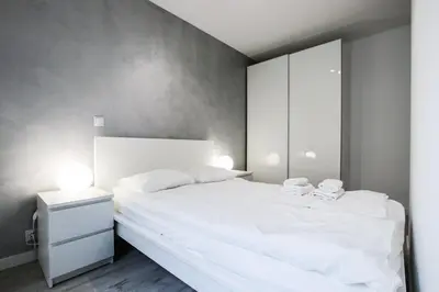 a bedroom with a white bed and a white cabinet at ApartmentPrestige - Boulevard in Kraków