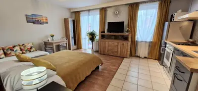 a room with a bed and a kitchen with a television at Cozy modern Apartment SUNRISE studio 35m2 balcony 3 persons in Kraków