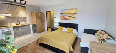 a large bedroom with a bed and a kitchen at Cozy modern Apartment SUNRISE studio 35m2 balcony 3 persons in Kraków