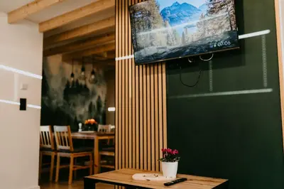 a dining room with a table and a television on a wall at Domki pod Kamionna in Laskowa