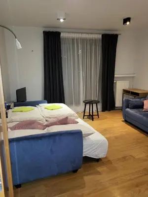 a bedroom with two beds and a blue couch at Amber Hostel Szlak in Kraków