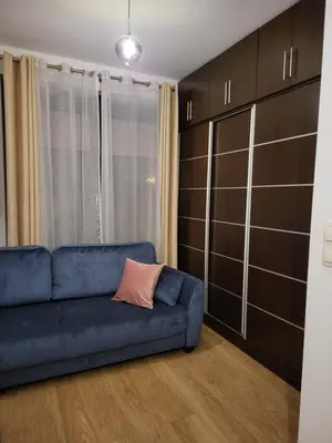 a blue couch in a living room with a window at Amber Hostel Szlak in Kraków