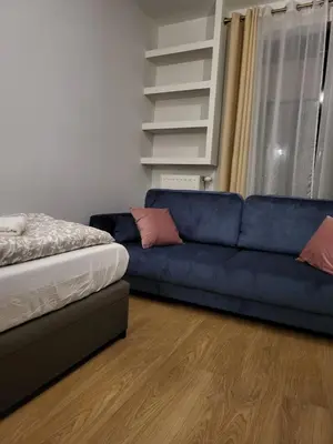 a living room with a blue couch and a bed at Amber Hostel Szlak in Kraków