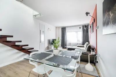 a living room with a couch and a television and a staircase at Radziwillowska Old Town Deluxe Apartment WAWELOFTS in Kraków