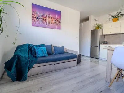 a living room with a blue couch and a kitchen at Miły czas in Kraków