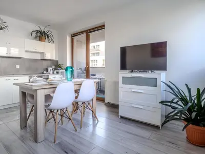 a kitchen with a wooden table and white chairs at Miły czas in Kraków