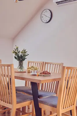 a dining room table with chairs and a clock on the wall at WieliczkaHome 1st floor + garden + parking in Wieliczka