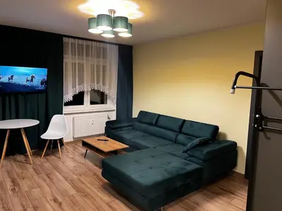 a living room with a green couch and a table at Komfortowy Apartament w centrum in Jaworzno