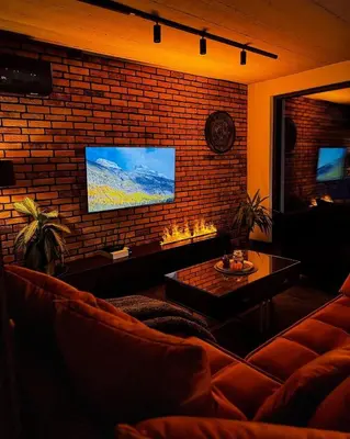 a living room with a couch and a tv on a brick wall at Babiogórskie Stodoły in Zawoja