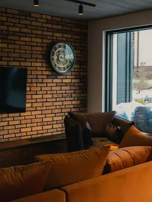 a living room with couches and a clock on a brick wall at Babiogórskie Stodoły in Zawoja