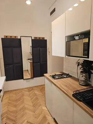 a kitchen with white cabinets and a wooden counter top at Apartamenty Lenart in Kraków