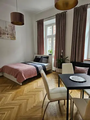 a bedroom with a bed and a dining room at Apartamenty Lenart in Kraków