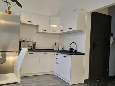 a white kitchen with white cabinets and a sink at Apartamenty Lenart in Kraków