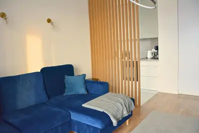 a blue couch in a living room with a kitchen at Apartament na wynajem 32 m2 in Bochnia