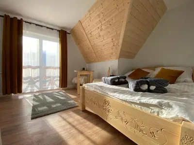 a bedroom with a large bed and a large window at Willa Pod Wyciągiem in Spytkowice