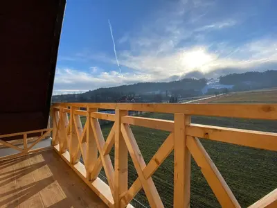 a wooden balcony with a view of a field at Willa Pod Wyciągiem in Spytkowice