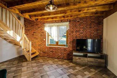 a living room with a television and a brick wall at Wierchy Beskidu in Dobra