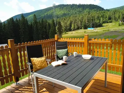 a wooden table and chairs on a wooden deck at Wierchy Beskidu in Dobra