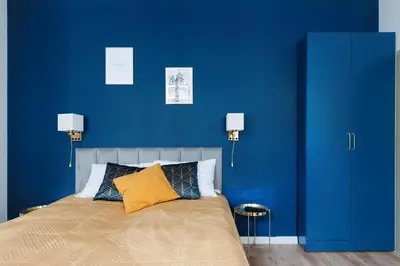 a blue bedroom with a bed with a blue wall at Rose apartment in Kraków