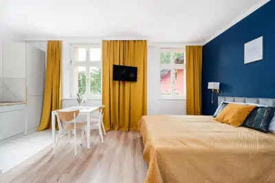 a bedroom with a bed and a table and yellow curtains at Rose apartment in Kraków