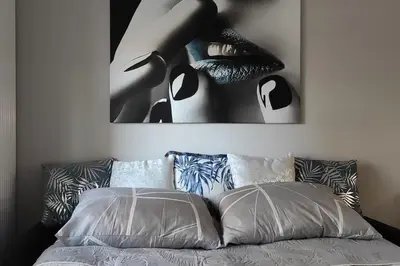 a bed with two pillows and a picture of a woman at Nowoczesny apartament w pobliżu centrum in Kraków