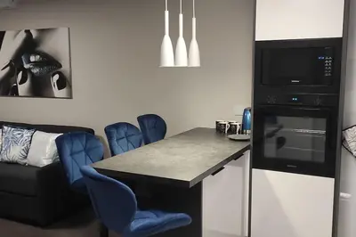 a kitchen with a counter with blue chairs and a microwave at Nowoczesny apartament w pobliżu centrum in Kraków