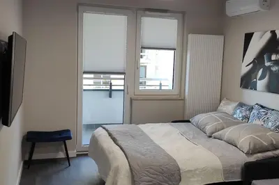 a bedroom with a large bed and two windows at Nowoczesny apartament w pobliżu centrum in Kraków