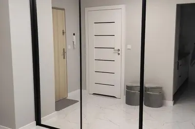 two mirrors in a room with a door and a trashcan at Nowoczesny apartament w pobliżu centrum in Kraków