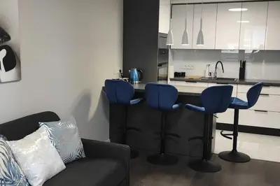 a kitchen with blue bar stools and a counter at Nowoczesny apartament w pobliżu centrum in Kraków