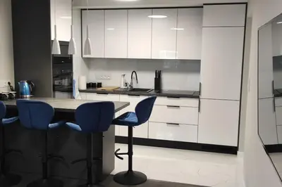 a kitchen with a table and two blue chairs at Nowoczesny apartament w pobliżu centrum in Kraków